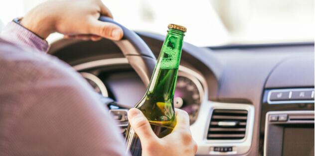 Man driving with a beer bottle on his hand