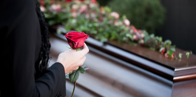 Persona con una rosa en la mano en un funeral